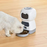 Distributeur de croquettes pour chat NutriZen avec un chat blanc mangeant sur un sol en bois. - ambiance cosy
